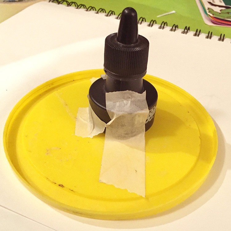 Taping your ink bottle to a base stops most spills before they happen! We use modeling clay to stick our bottles onto a plastic plate.